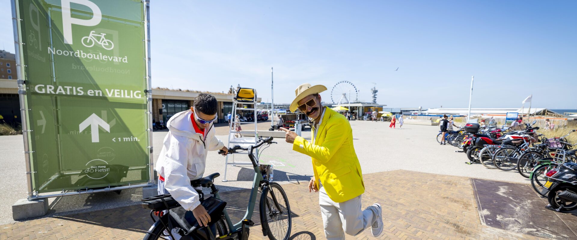 Actie fietsenstalling Noordboulevard Scheveningen. Acteur verwijst naar de stalling voor een beszoeker.