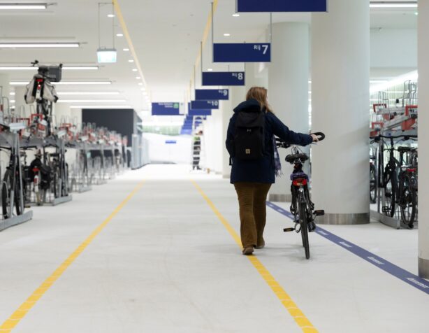 Fietsenstalling bij Den Haag Centraal. Fietser loopt door het gangpad van de stalling.